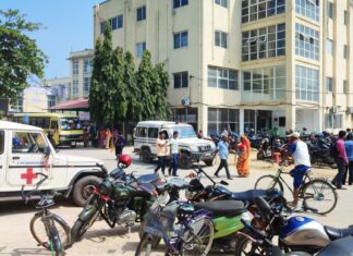 जनकपुर प्रादेशिक अस्पतालको भवनअगाडि एम्बुलेन्स, मोटरसाइकल, साइकल र मानिसहरू।