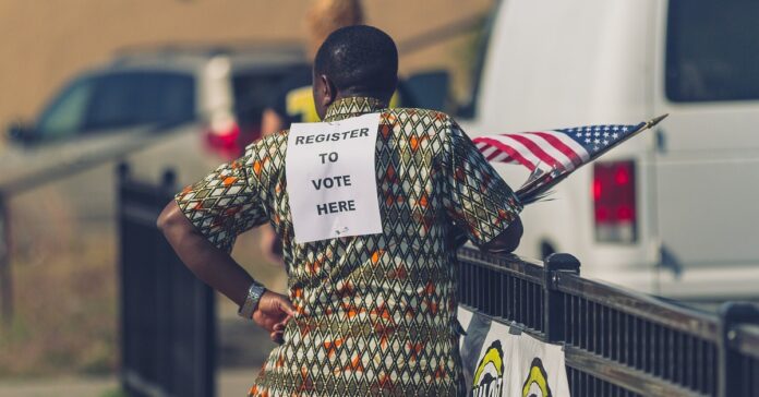 उत्तरी मिनियापोलिसमा ‘Register to Vote Here’ चिन्ह लगाएका मतदाता दर्ता स्वयंसेवक, फाइल तस्बिर
